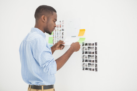 Concentrated businessman standing and reading document in the officeの写真素材