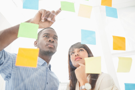 Focused teamwork looking at sticky notes in the officeの写真素材