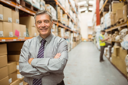 Smiling businessman with crossed arms in a large warehouse