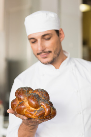 Baker checking freshly baked bread in the kitchen of the bakeryの写真素材