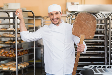 Smiling baker looking at camera in the kitchen of the bakeryの写真素材