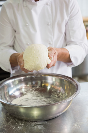 Baker forming dough in mixing bowl in the kitchen of the bakeryの写真素材
