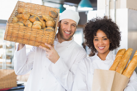 Team of bakers smiling at camera in the kitchen of the bakery
