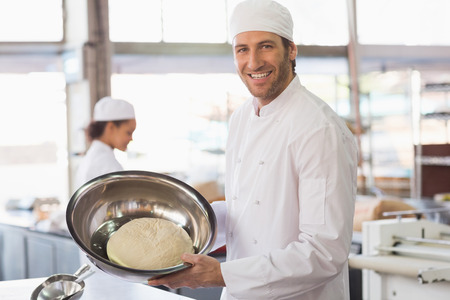 Baker showing dough in mixing bowl in the kitchen of the bakery