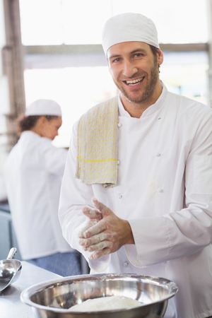 Baker clapping flour from his hands in the kitchen of the bakeryの写真素材