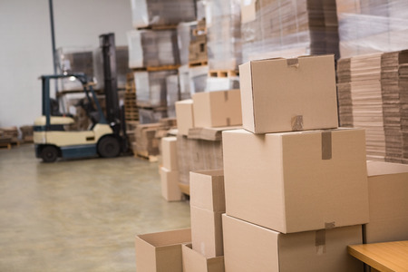 Forklift amid rows of boxes in a large warehouseの写真素材