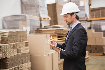 Serious warehouse manager checking inventory in warehouseの写真素材