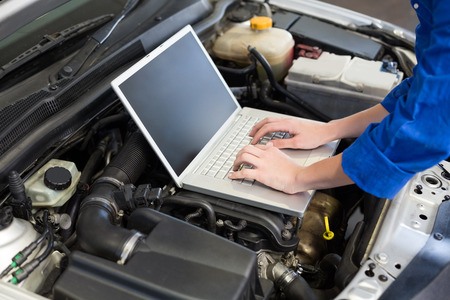 Mechanic using laptop on car at the repair garageの写真素材
