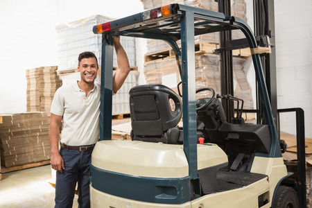 Manual worker leaning against the forklift in warehouseの写真素材