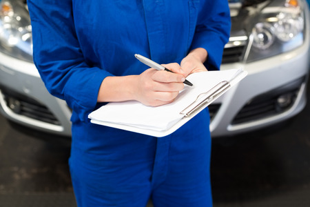 Mechanic writing on clipboard at the repair garageの写真素材
