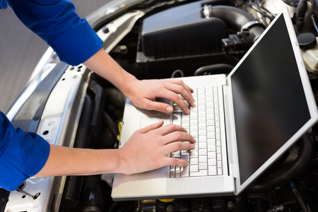 Mechanic using laptop on car at the repair garage