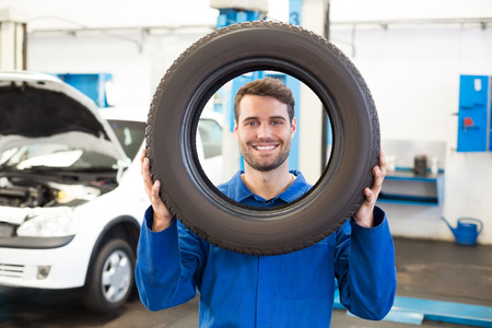 Mechanic holding a tire wheel at the repair garageの写真素材