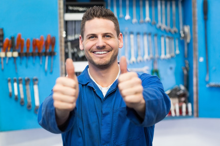 Smiling mechanic looking at camera at the repair garageの写真素材