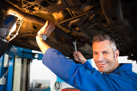 Mechanic examining under the car at the repair garageの写真素材
