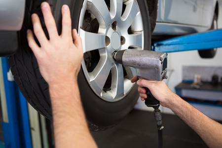 Mechanic adjusting the tire wheel at the repair garageの写真素材