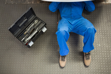 Mechanic lying and working under car at the repair garageの写真素材