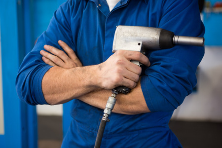 Mechanic holding a drill tool at the repair garageの写真素材