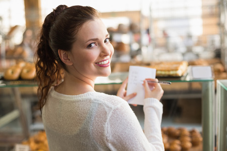 Woman checking her shopping list at the bakeryの写真素材
