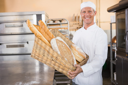 Baker showing basket of bread in the kitchen of the bakery