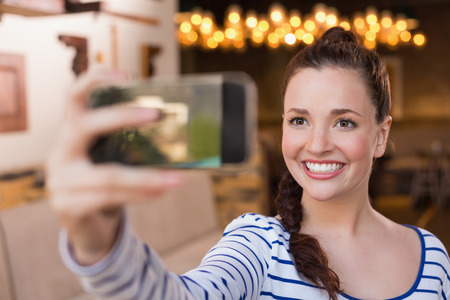 Young woman taking a selfie at the cafeの写真素材