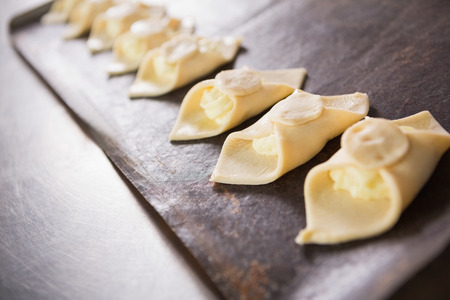 Close up of baker holding tray of raw dough in the kitchen of the bakery