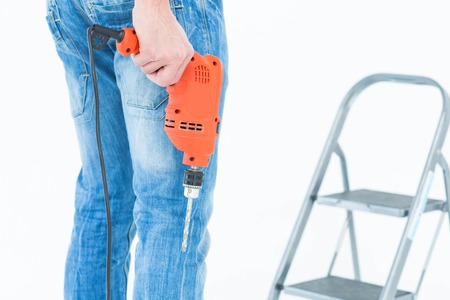 Cropped image of worker holding drill in front of step ladder over white backgroundの写真素材