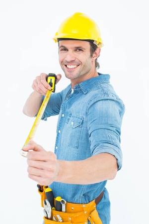 Portrait of happy male architect holding tape measure over white background