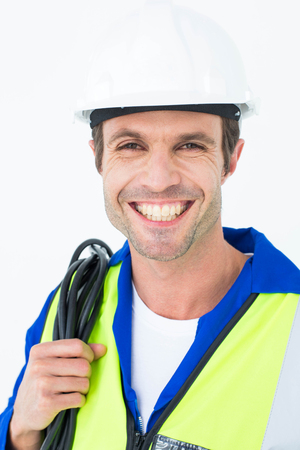 Portrait of happy electrician with wire against white background