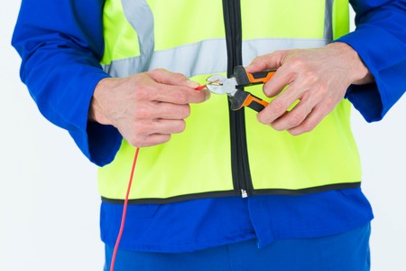 Cropped image of electrician cutting wire with pliers over white backgroundの写真素材