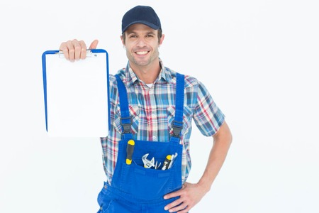 Portrait of confident plumber showing blank clipboard over white background