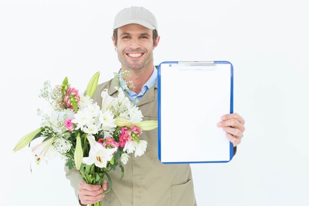 Portrait of happy delivery man holding bouquet and clipboard against white backgroundの写真素材