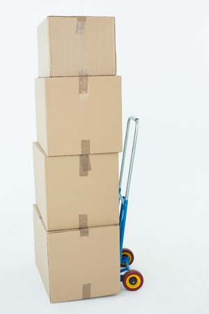 Stack of cardboard boxes on trolley over white backgroundの写真素材