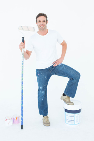 Full length portrait of man with paint bucket and roller on white backgroundの写真素材