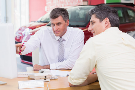 Businessman pointing his finger at screen at new car showroomの写真素材