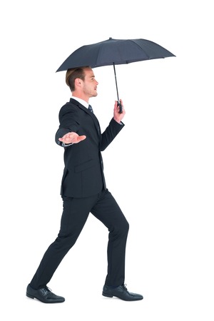 Concentrated businessman with umbrella walking on white backgroundの写真素材