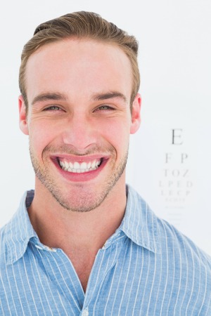 Happy handsome in shirt in front of eye test on white backgroundの写真素材