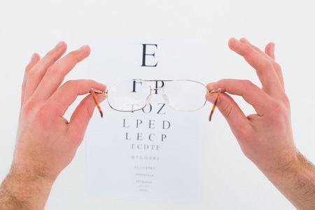 Hands holding glasses for eye test on white backgroundの写真素材