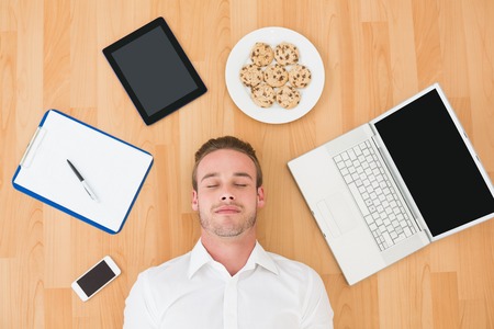 Man lying on floor surrounded by various objects at home in the living room