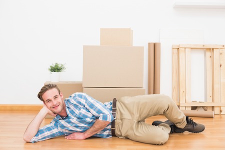 Happy man posing with moving boxes at home in the living room