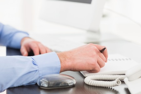 Hand of businessman writing on notebook in his officeの写真素材