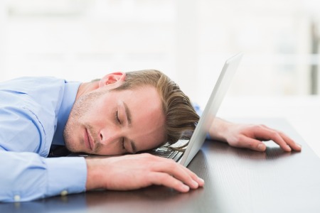 Businessman sleeping on his laptop in the officeの写真素材