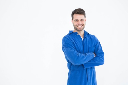 Portrait of smiling young male machanic standing arms crossed on white backgroundの写真素材