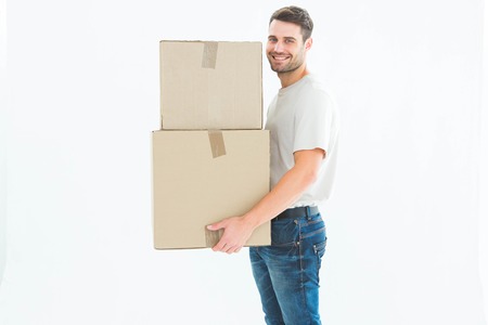 Full length portrait of happy delivery man carrying cardboard boxes on white background