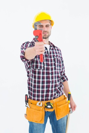 Portrait of male handyman looking through adjustable wrench on white background