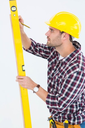 Side view of technician marking while using spirit level on white background