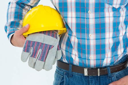 Close-up of construction worker holding hard hat and gloves on white backgroundの写真素材