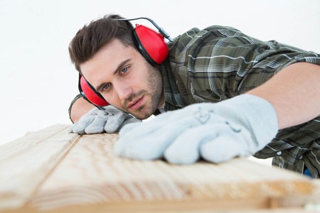 Male carpenter measuring wooden plank on white backgroundの写真素材
