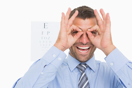 Businessman surrounds his eyes with fingers on white background