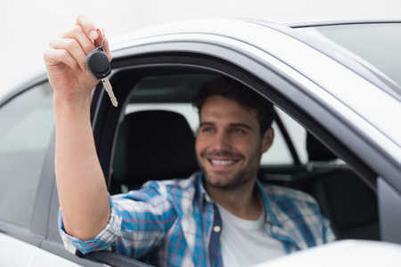Young man smiling and holding key in his carの写真素材