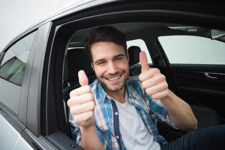 Young man smiling at camera in his carの写真素材